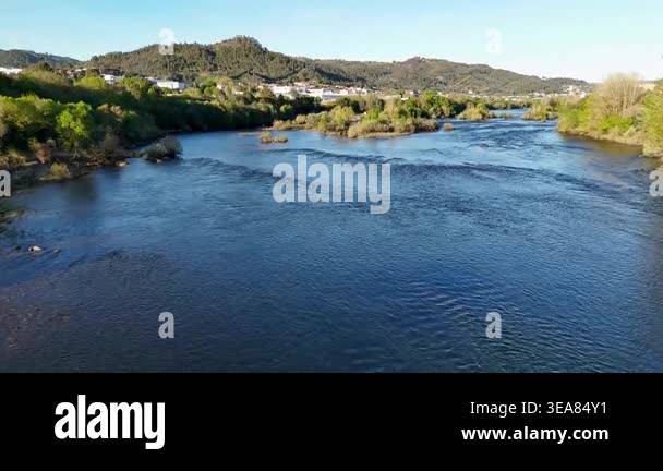 Calm river water flowing peacefully through a valley with green hills ...