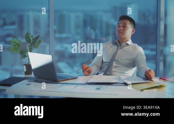 asian manager leaning back in chair with pencil in hand, blueprint and ...