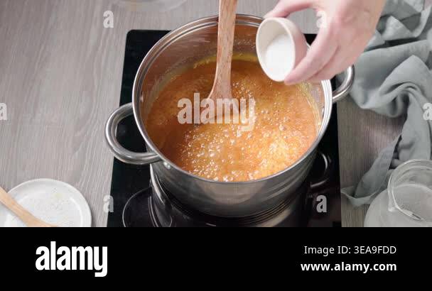 Close up of hot homemade caramel sauce boiling in a pot on a stove ...