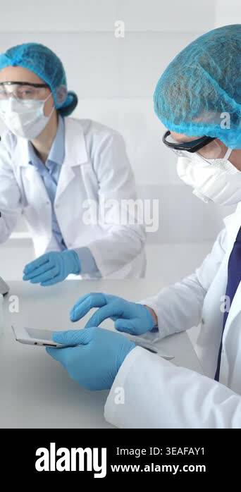 A male scientist in a protective mask and glasses takes notes on a ...