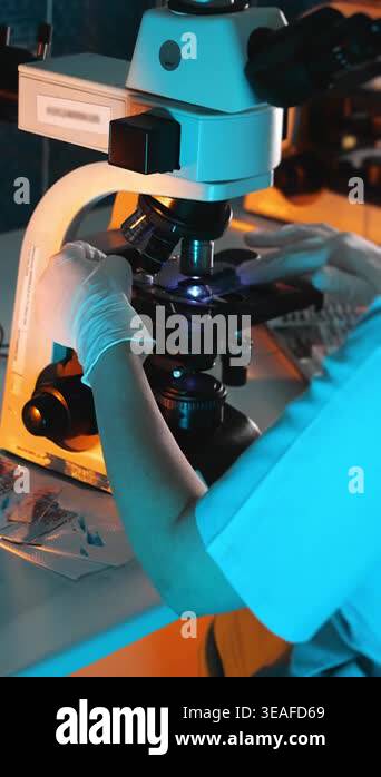 Laboratory technician placing sample slide under microscope, scientific ...
