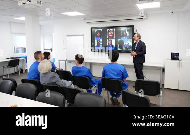 Professional audience of nurses in blue scrubs attending a hybrid ...