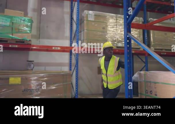African American man wearing safety gear in a warehouse near stacked ...