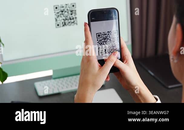 Person scanning QR code from computer screen with smartphone at home ...