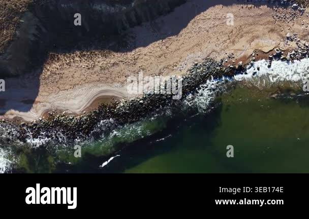 A sandy beach is located next to a rocky shore where the ocean waves ...