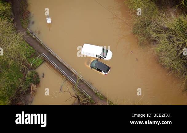 Rural Rising Vehicle Storm flooding in UK submerging rural road and vehicles in muddy river ...