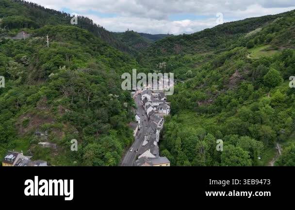 Aerial drone view of small village in green valley surrounded by forest ...