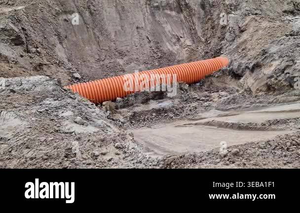 Orange corrugated pipe in a trench at a construction site. Plastic ...
