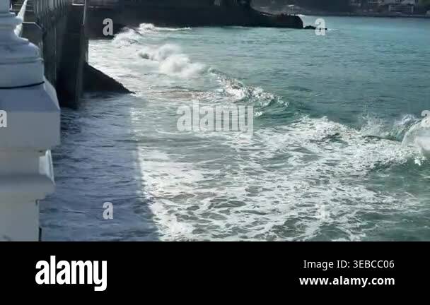 4K video of ocean waves breaking at pier base filmed from promenade ...