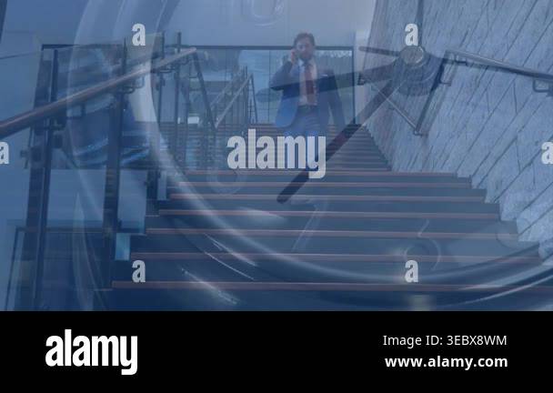 Man descending stairs in business lobby, calling on phone and causing ...