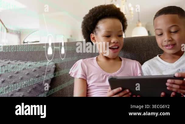 Girl tapping tablet on couch as binary overlay from left, boy sharing ...