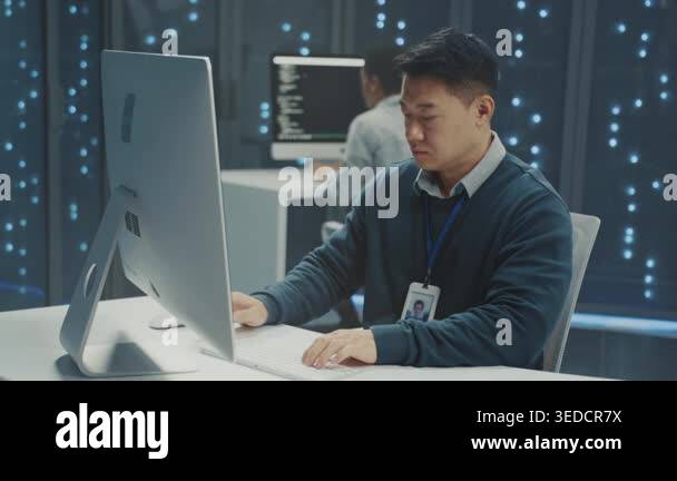 system engineer typing machine learning server code... asian it engineer typing at desktop workstation focused on code and ...