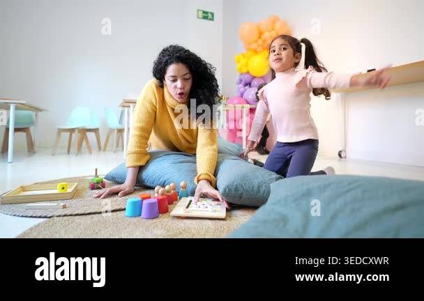 Diligent teacher guiding a playful little girl through an educational ...