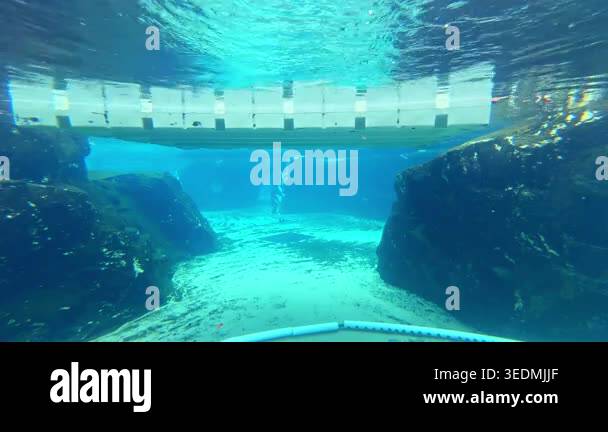 Clear water in a deep pool reveals large rocks at the bottom. A ...