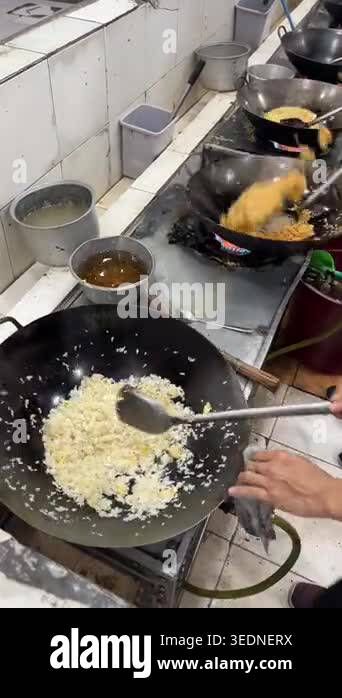 Professional chefs cooking fried rice and stir-fry vegetables in large ...