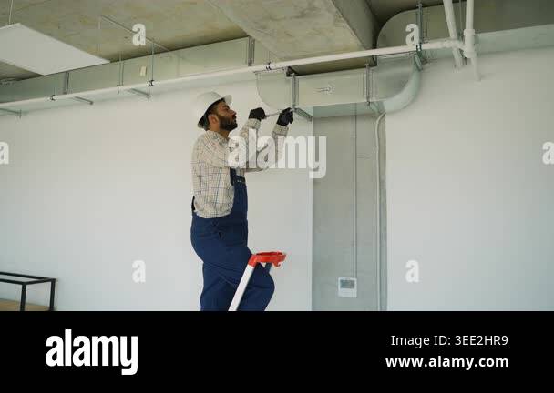 Male hvac technician installing ventilation and air conditioning system ...