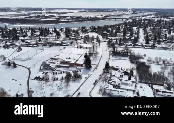 Aerial view of a snowy river flowing through a quiet residential area ...
