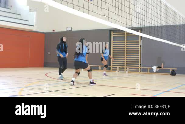 Diverse female teammates receiving volleyball serve shifting stance ...