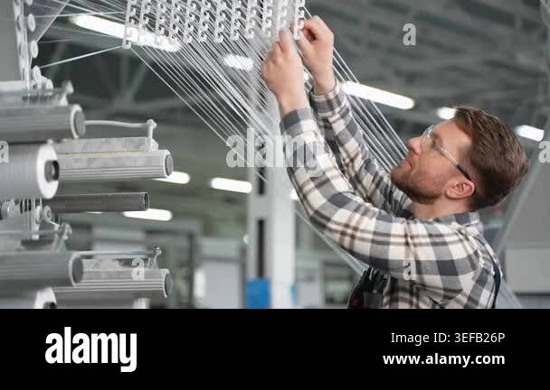 Young male operator in safety glasses meticulously setting up threads ...