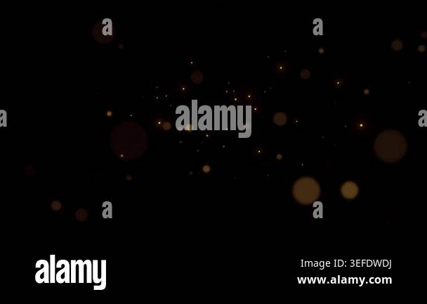 Luminous golden particles gently drift and twinkle across a deep black ...