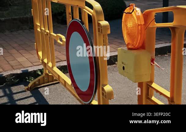 Round prohibitive signboard and flashing amber lamp blocking street for ...