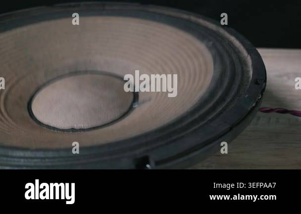 A close-up view of a large black subwoofer cone vibrating intensely ...
