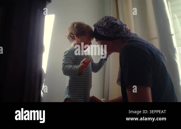 Mother helps child get dressed and playfully interacts, encouraging ...
