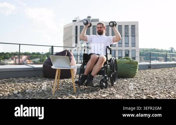 A determined man with a beard and long hair, seated in a wheelchair ...