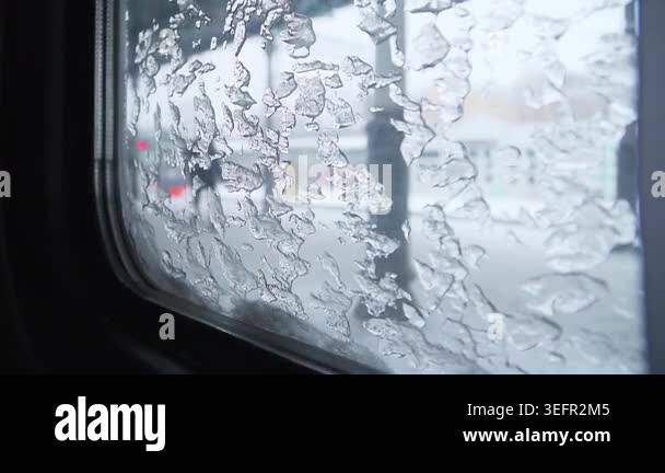 Frosted window view, gradually revealing a snowy street scene with ...