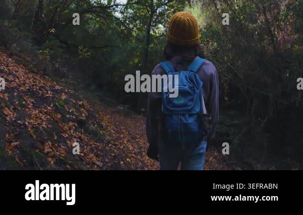A teenage tourist with a backpack walks along a rocky forest path ...