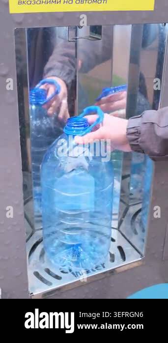 Close up of a person filling a big blue water bottle with fresh ...