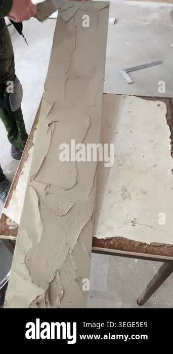 A craftsman spreads gray mortar with a trowel across the surface of ...