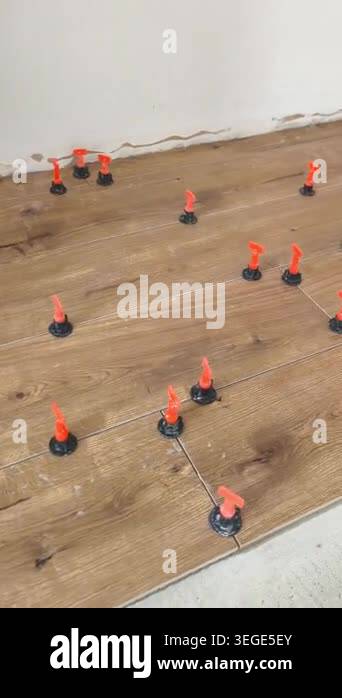 Wood-textured ceramic floor tiles being installed, with plastic ...