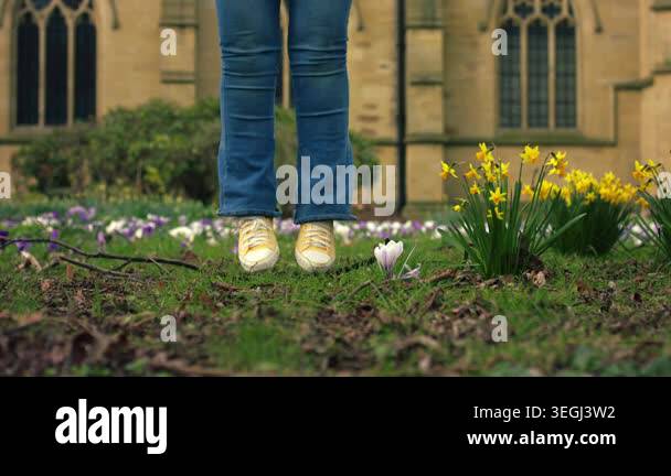 Woman celebrates Easter jumping in church yard through yellow daffodil ...