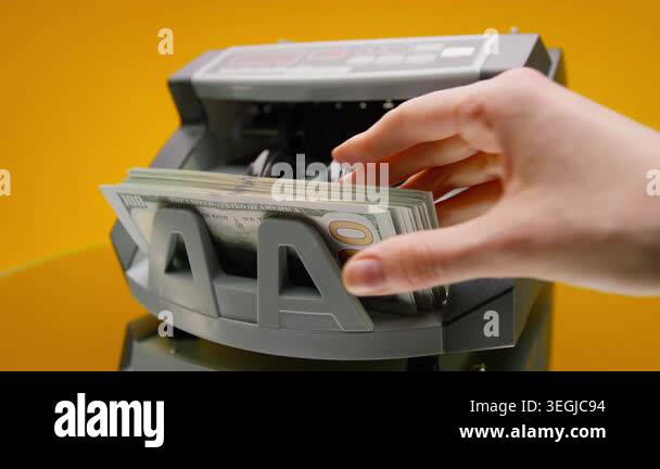 Close-up of a hand taking US dollar bills from a money counting machine ...
