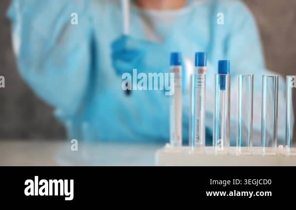 Laboratory worker in protective clothing preparing sample tubes for ...
