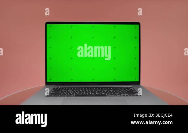 Close-up laptop with bright green chroma key screen on pink background ...