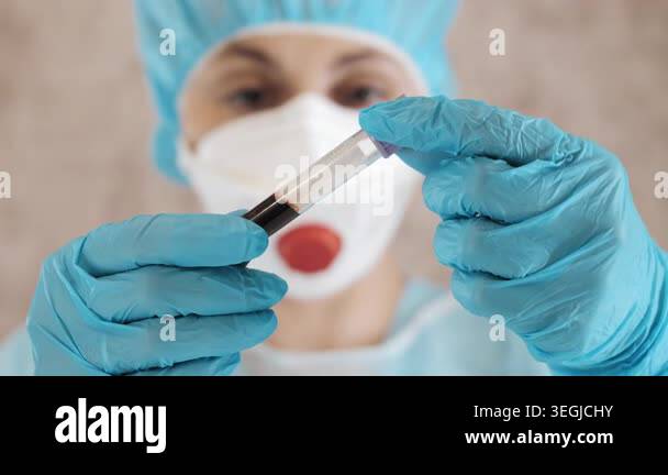 Close up of laboratory scientist in protective gear examining blood ...