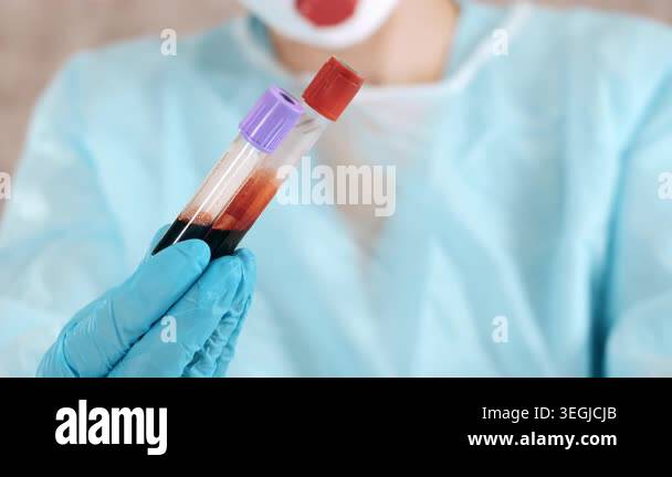 Close up of laboratory worker in protective clothing holding blood ...