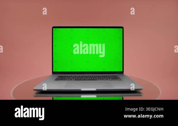 Open laptop with bright green chroma key screen on a reflective table ...