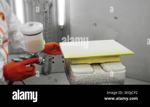 Industrial worker applying paint coating to furniture panel with spray ...