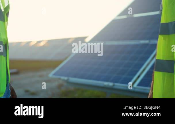 two workers handshake beside solar panels at sunset, closeup shot ...