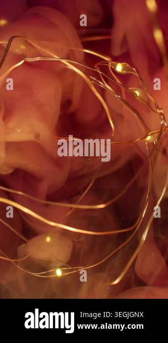 Vertical video. Ink drop. Fairy light. Defocused pink yellow golden ...