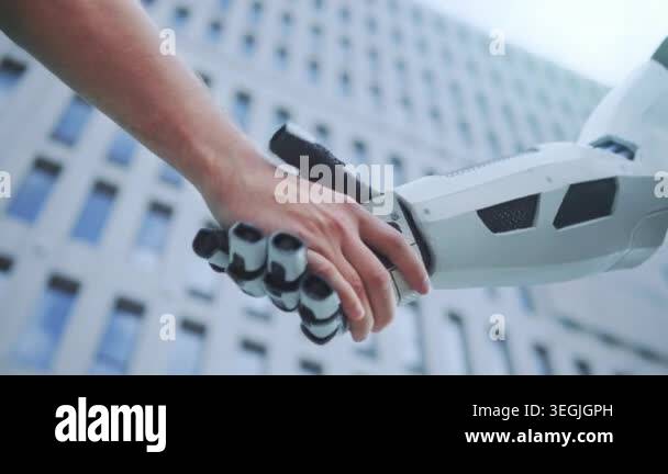 white hand shakes robotic arm against modern facade, firm handshake ...