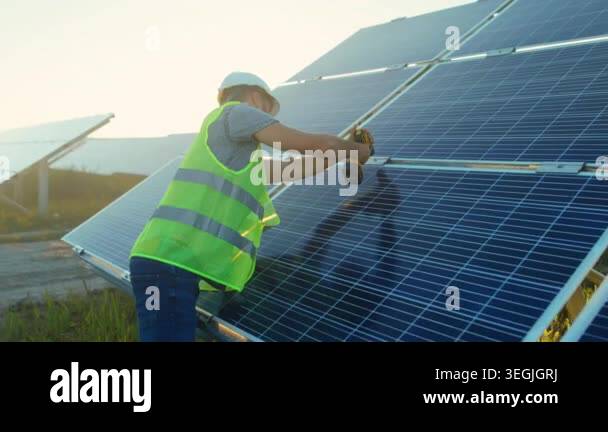 technician installing solar panel at sunset, drilling mounts on ...