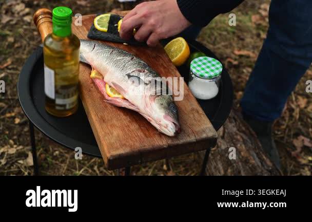 Close up of male hands stuffing fish with lemon slices before cooking ...