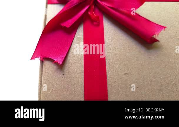 Cardboard gift box wrapped with a vibrant red satin ribbon and a large ...