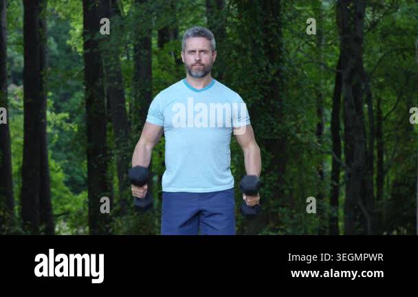 Outdoor strength training dumbbells. Lift dumbbells for fitness. Man ...