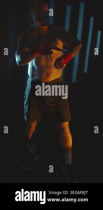 A man practices boxing in a dark gym, focusing on his movements and ...
