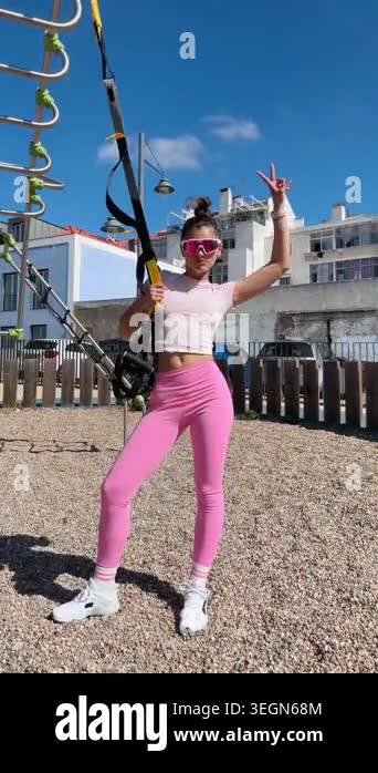 Outdoor suspension training caucasian woman in pink leggings and crop ...